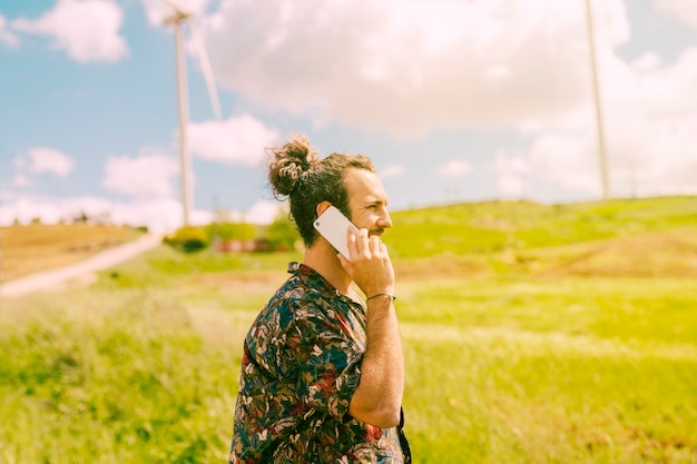 Gratis foto jong mannetje dat op mobiele telefoon op landelijk spreekt