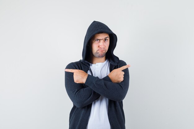 Jong mannetje dat weg in t-shirt, jasje wijst en aarzelend kijkt. vooraanzicht.