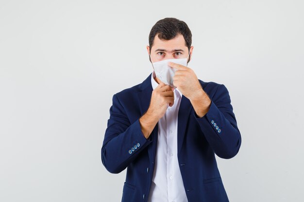 Jong mannetje dat zijn medisch masker in overhemd aanpast