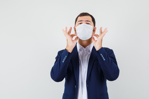 Jong mannetje dat zijn medisch masker in overhemd aanpast