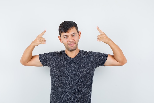 Jong mannetje in zwart t-shirt dat en tevreden, vooraanzicht benadrukt kijkt.