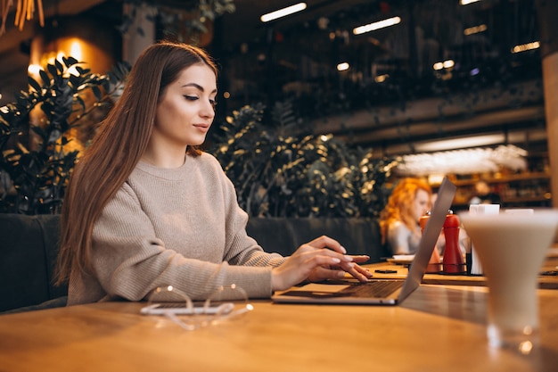 Jong meisje dat aan een computer in een koffie werkt