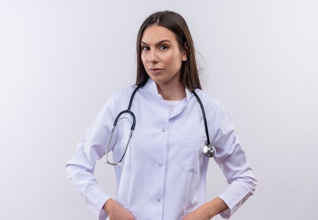 jong meisje dat een stethoscoop medische jurk draagt op geïsoleerde witte muur
