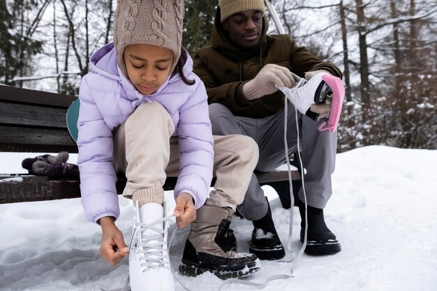 Jong meisje dat haar schaatsen aantrekt met de hulp van haar vader