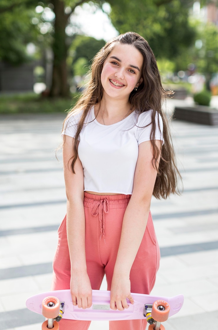 Gratis Foto jong meisje dat haar skateboard buiten houdt