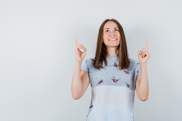 Jong meisje dat in t-shirt benadrukt en hoopvol, vooraanzicht kijkt.