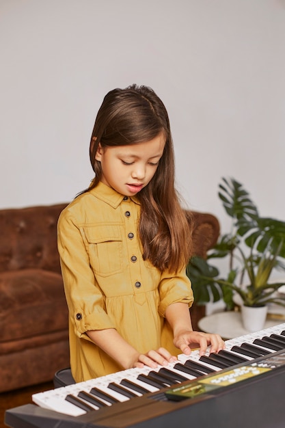 Jong meisje dat leert hoe het elektronische toetsenbord te spelen