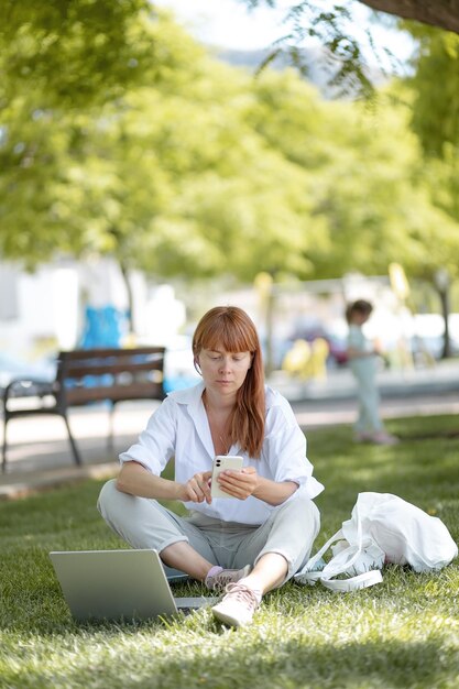 Jong meisje dat op een computer in het park werkt