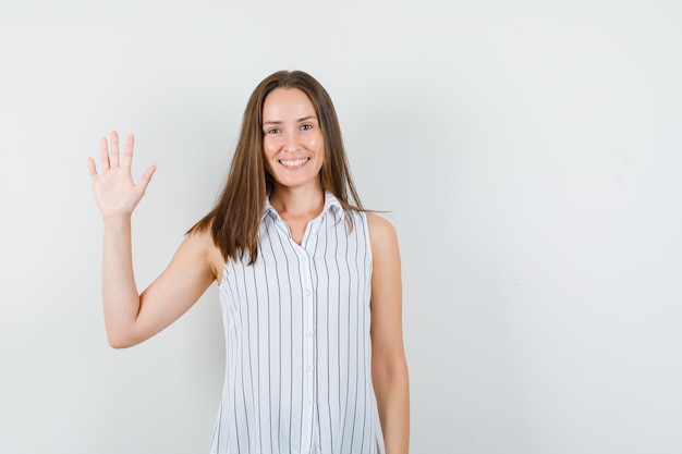 Jong meisje dat palm voor groet in t-shirt toont en optimistisch kijkt. vooraanzicht.