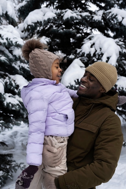 Jong meisje dat plezier heeft met haar vader op een besneeuwde winterdag