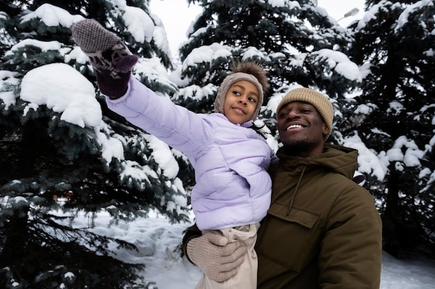 Jong meisje dat plezier heeft met haar vader op een besneeuwde winterdag