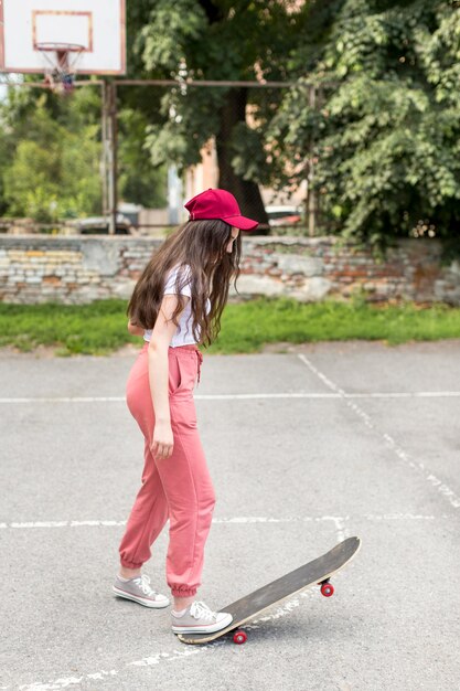 Jong meisje dat trucs met haar skateboard doet