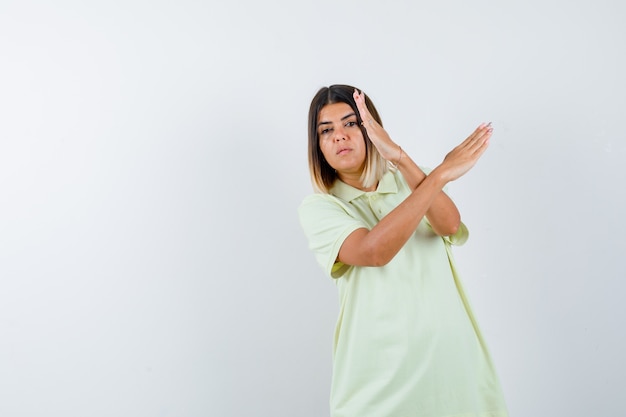 Jong meisje dat twee gekruiste armen houdt, geen teken in t-shirt gebaart en zelfverzekerd kijkt, vooraanzicht.