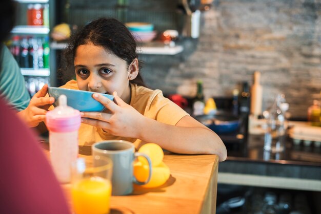 Jong meisje dat voedsel in een kom eet bij de eettafel