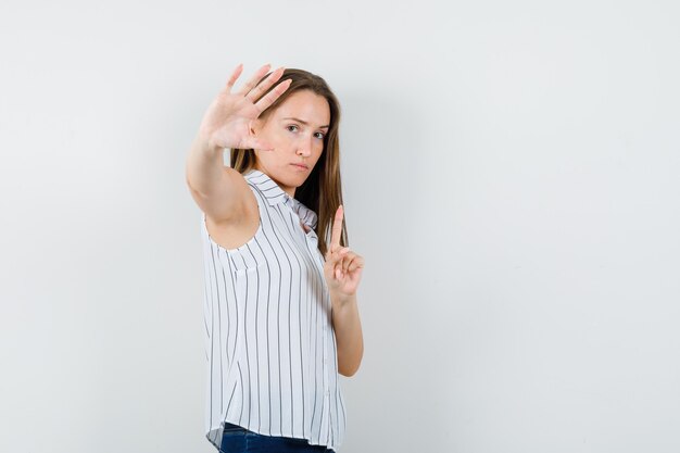 Jong meisje dat wacht een minuutgebaar in t-shirt, jeans toont en ernstig kijkt. .