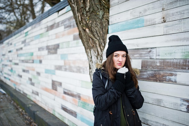 Jong meisje draagt zwarte hoofddeksels tegen houten muur