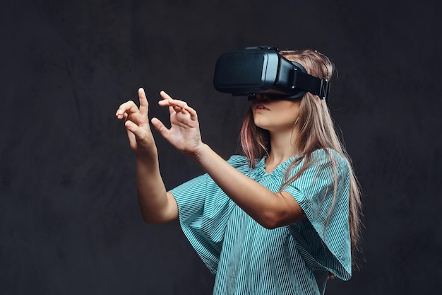 Jong meisje gekleed casual met behulp van virtual reality-bril. Geïsoleerd op donkere gestructureerde achtergrond.