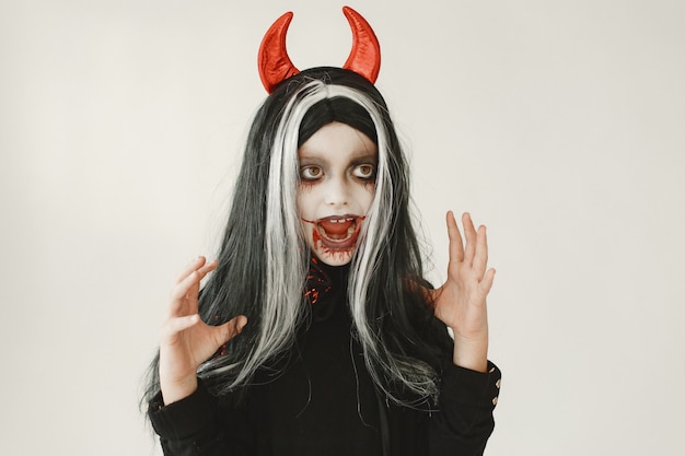 Gratis foto jong meisje gekleed in zwarte jurk als duivel heeft twee rode hoorns op haar hoofd