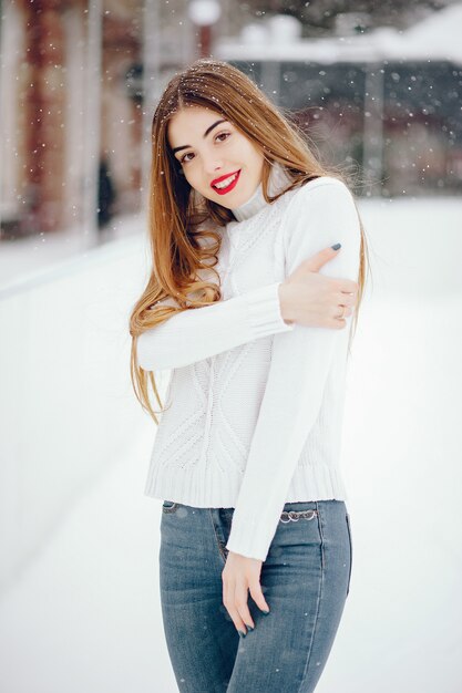 Jong meisje in een witte sweater die zich in een de winterpark bevindt