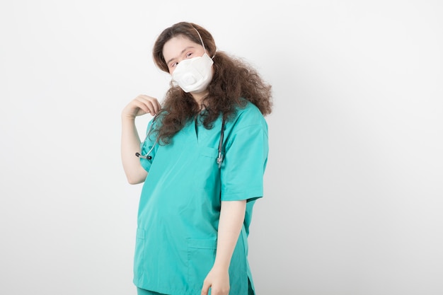 Jong meisje in groen uniform met medisch masker.