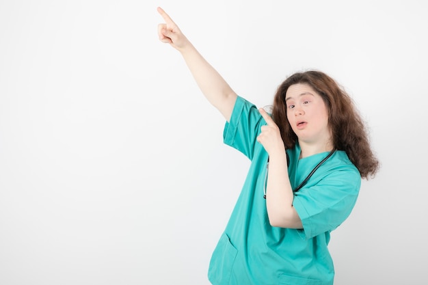 jong meisje in groen uniform staande en wegwijzend.