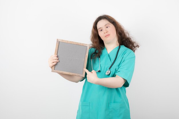 jong meisje in groen uniform wijzend op een frame.