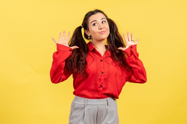 Jong meisje in rode blouse op geel