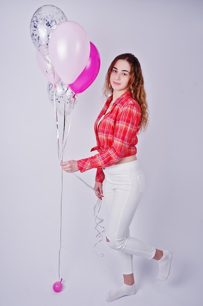 Gratis foto jong meisje in rood geruit overhemd en witte broek met ballonnen tegen een witte achtergrond op studio