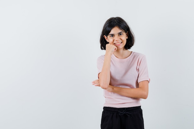 Jong meisje in roze t-shirt en zwarte broek met heavy metal gebaar en pinkvinger en op zoek gelukkig