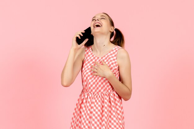 jong meisje in schattige lichte jurk praten over de telefoon en lachen op roze