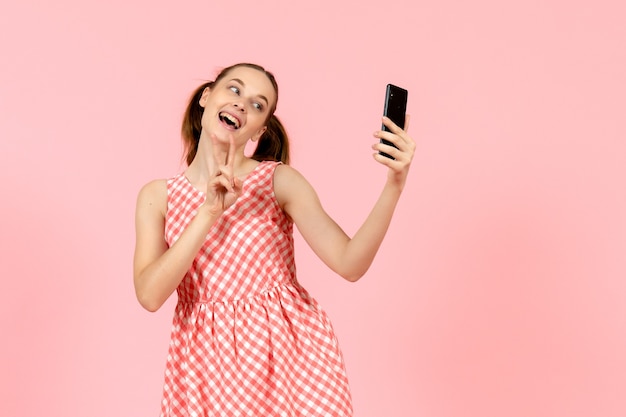 Jong meisje in schattige lichte jurk selfie te nemen op roze