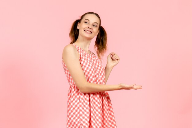 jong meisje in schattige roze jurk met lachende uitdrukking op roze