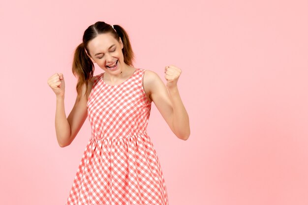 jong meisje in schattige roze jurk met vreugde uitdrukking op roze