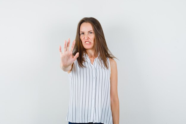 Jong meisje in t-shirt, jeans die weigeringsgebaar tonen en boos, vooraanzicht kijken.