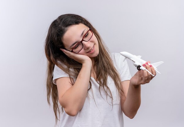 Jong meisje in wit t-shirt met speelgoed vliegtuig te kijken met een dromerige blik