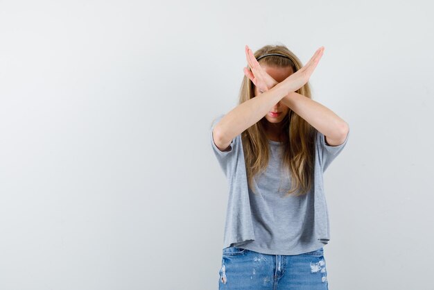 Jong meisje kruist haar armen en kijkt naar beneden op een witte achtergrond