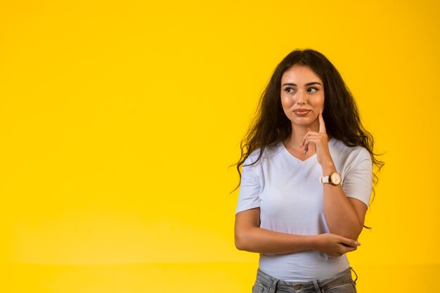 Jong meisje legt haar vinger op haar kin en glimlacht.