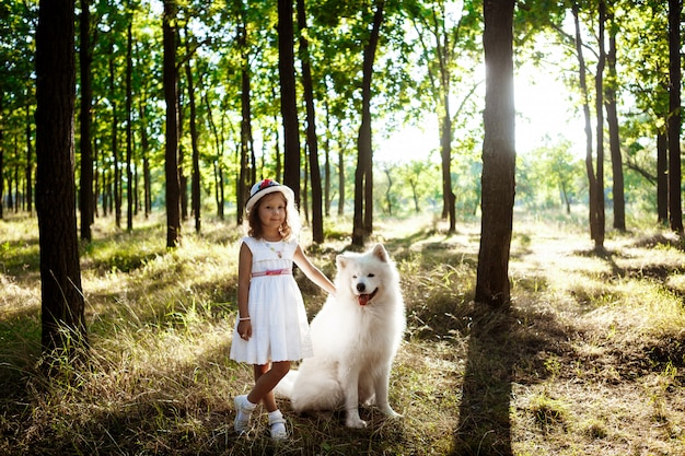 Jong meisje lopen, spelen met hond in park bij zonsondergang.