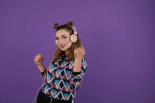 Jong meisje met creatieve make-up staan op paarse achtergrond. Hoge kwaliteit foto