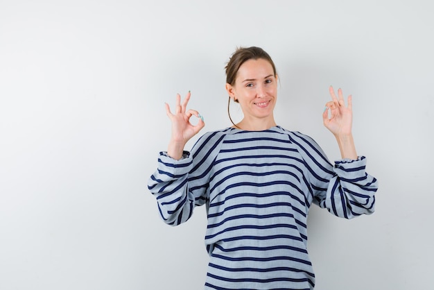 Jong meisje met een OK-handteken op een witte achtergrond