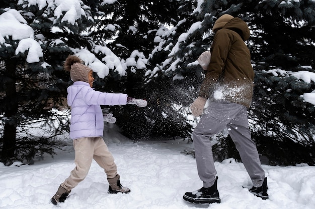 Jong meisje met een sneeuwgevecht met haar vader op een winterdag