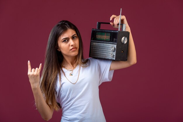 Jong meisje met een vintage radio op haar schouder en ziet er toegewijd uit.