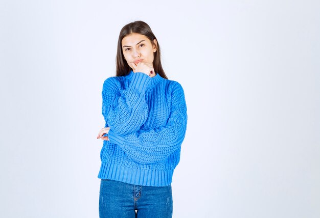 jong meisje model in blauwe trui permanent en poseren op wit-grijs.