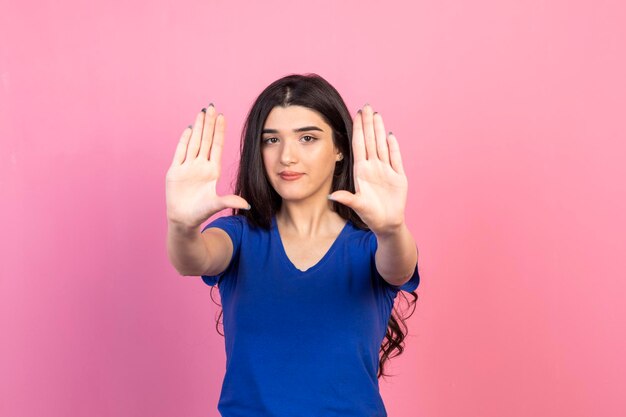 Jong meisje toont haar handen naar de camera en staat op roze achtergrond