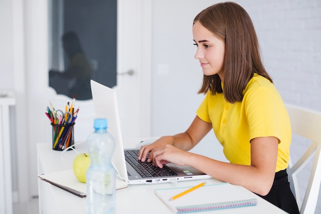 Jong meisje typend op de laptop thuis