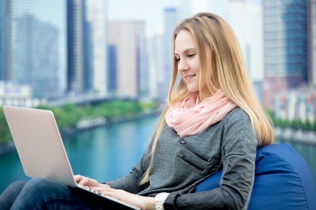 Jong meisje zitten met laptop, cityscape op de achtergrond