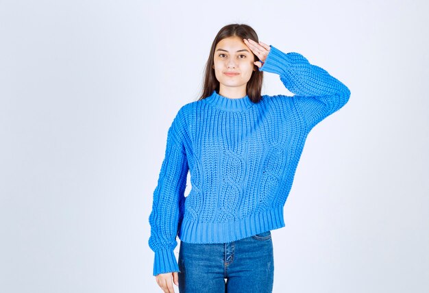 jong meisjesmodel in blauwe sweater die hand dichtbij voorhoofd houdt.