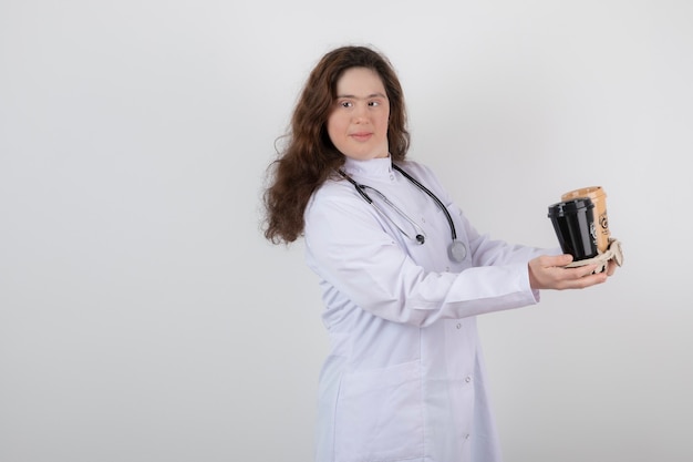 Jong model meisje in wit uniform met een karton met kopjes koffie.