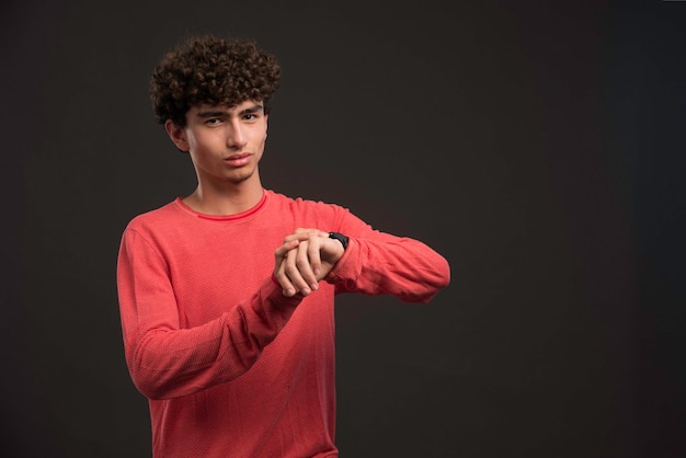 Jong model met krullende haren die zijn tijd controleren.