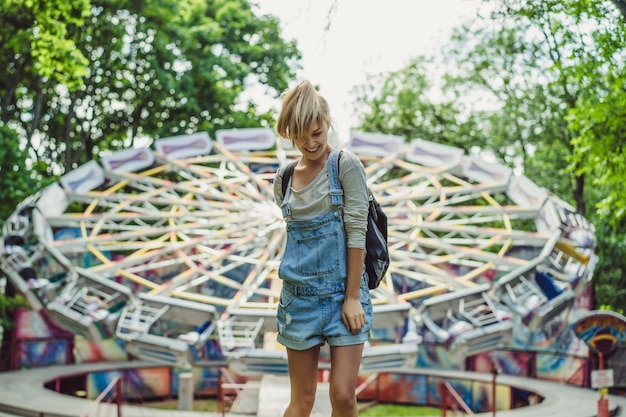 jong mooi blond meisje in denim globaal met rugzak het stellen in een pretpark